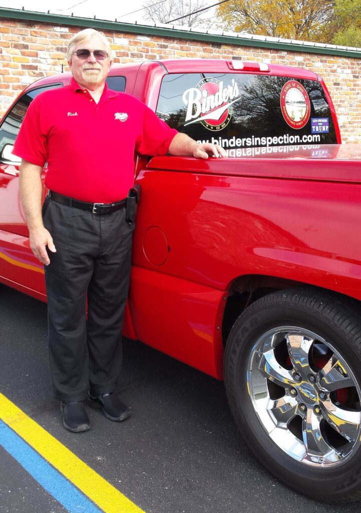 Man is wearing a red polo shirt, black trousers, black shoes, and sunglasses.